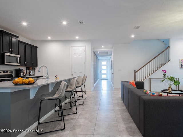 kitchen featuring sink, tasteful backsplash, a kitchen bar, a kitchen island with sink, and appliances with stainless steel finishes