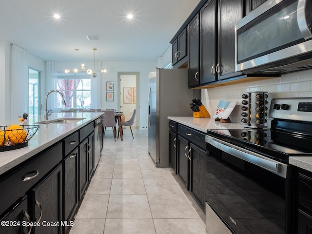 kitchen with sink, backsplash, pendant lighting, light tile patterned floors, and appliances with stainless steel finishes