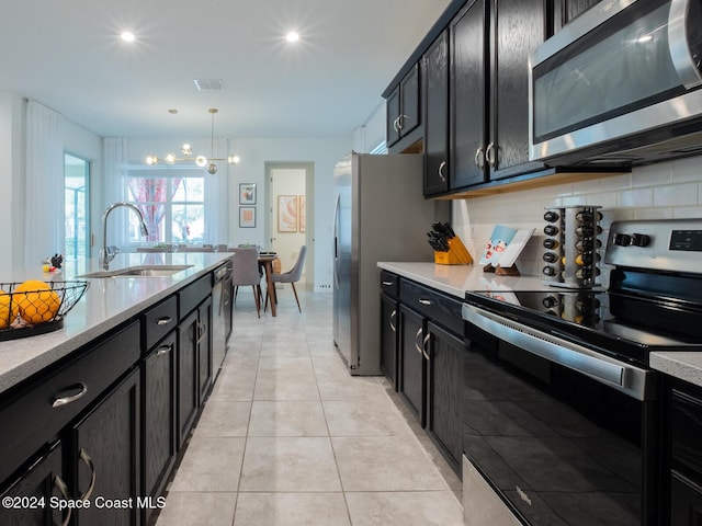 8933 Amelia Downs Trl, Kissimmee, FL 34747 - kitchen featuring stainless steel appliances, dark cabinets, backsplash, light tile patterned floors, and decorative light fixtures