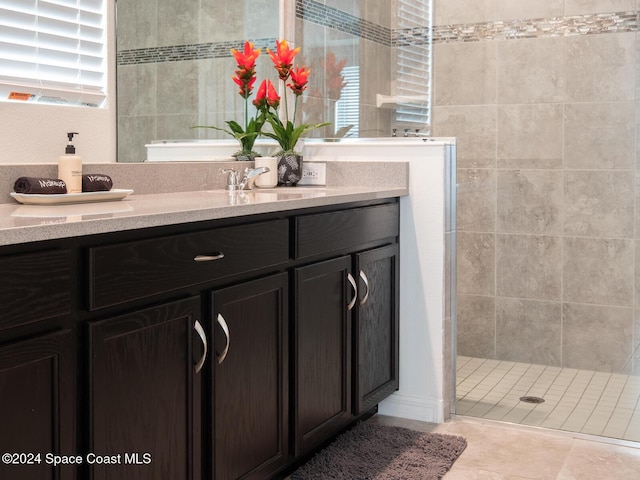 bathroom with tile patterned flooring, vanity, and walk in shower