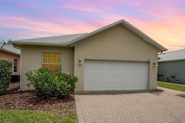 single story home featuring a garage and central air condition unit