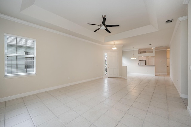 tiled empty room with ceiling fan, a raised ceiling, and crown molding