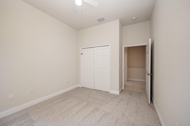 unfurnished bedroom featuring ceiling fan, a closet, and light colored carpet