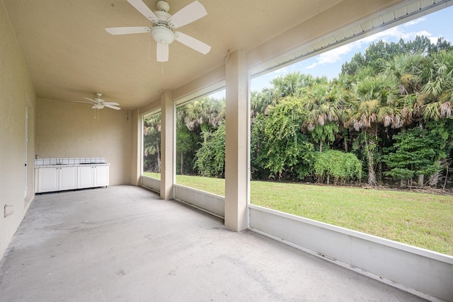 unfurnished sunroom featuring ceiling fan