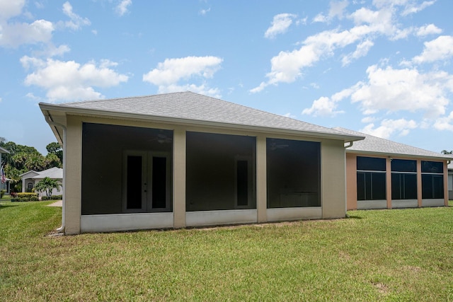 rear view of property with a lawn and a sunroom