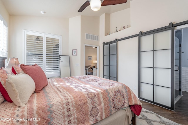 bedroom featuring ceiling fan, a barn door, lofted ceiling, and dark wood-type flooring