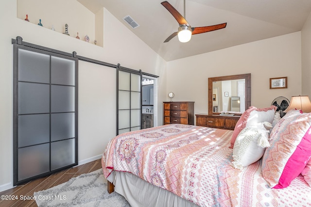 bedroom featuring ceiling fan, a barn door, dark hardwood / wood-style floors, and high vaulted ceiling