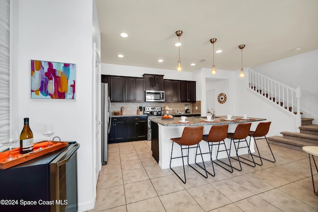 kitchen featuring a breakfast bar, hanging light fixtures, light tile patterned floors, light stone countertops, and stainless steel appliances