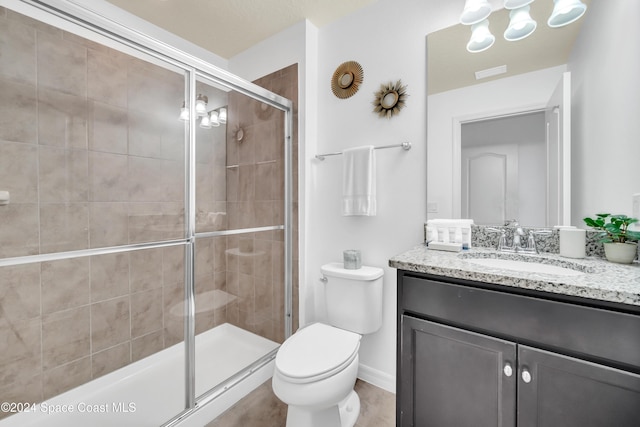 bathroom featuring vanity, a shower with shower door, and toilet