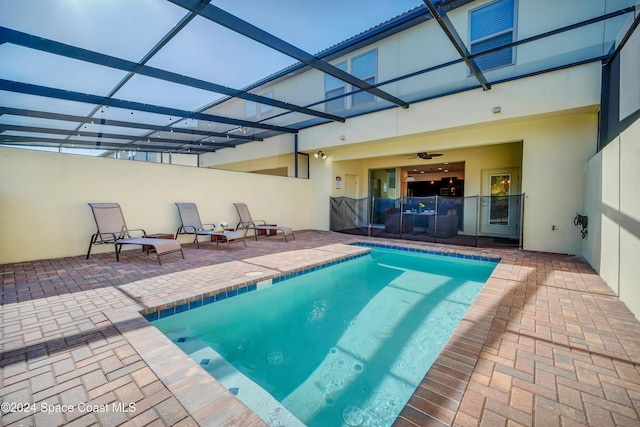 view of swimming pool featuring glass enclosure and a patio