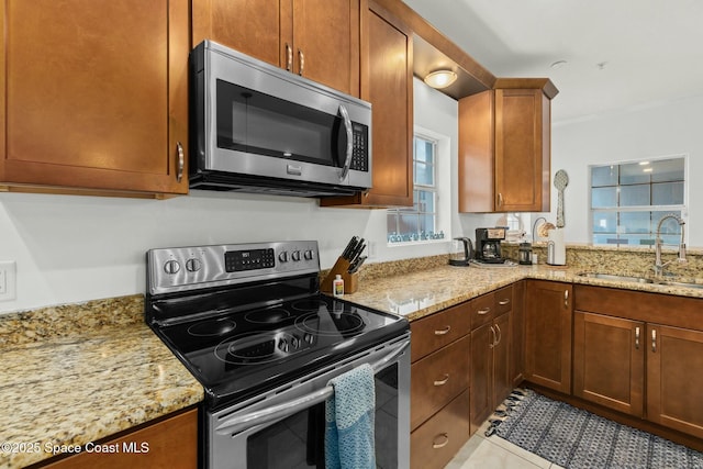 kitchen with light stone countertops, appliances with stainless steel finishes, light tile patterned floors, and sink