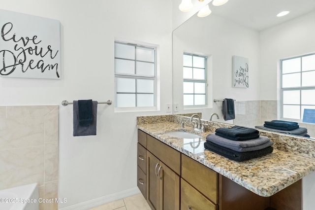 bathroom with tile patterned floors, a bathtub, vanity, and a healthy amount of sunlight