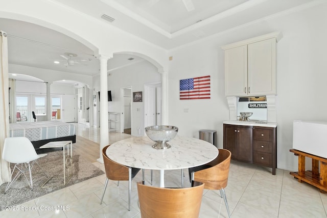 dining space with french doors, decorative columns, and a raised ceiling