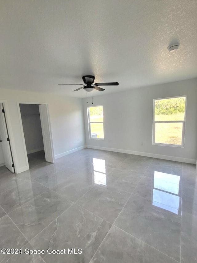 unfurnished room with a textured ceiling and ceiling fan