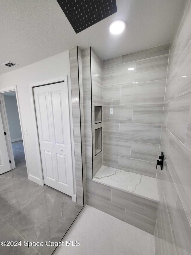 bathroom with a textured ceiling and tiled shower