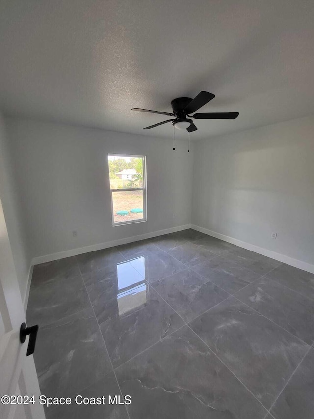 unfurnished room with ceiling fan and a textured ceiling