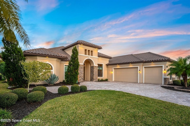 mediterranean / spanish house with a garage and a lawn