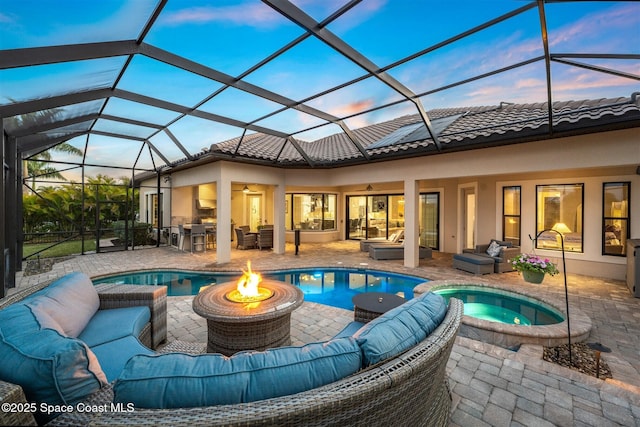 back house at dusk featuring a swimming pool with hot tub, an outdoor living space with a fire pit, and a lanai