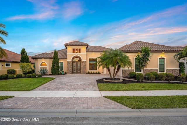 mediterranean / spanish-style house with a front yard and french doors