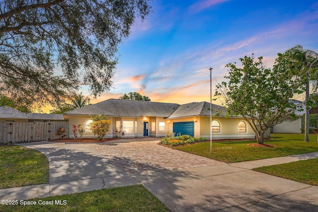 ranch-style house featuring a garage and a yard