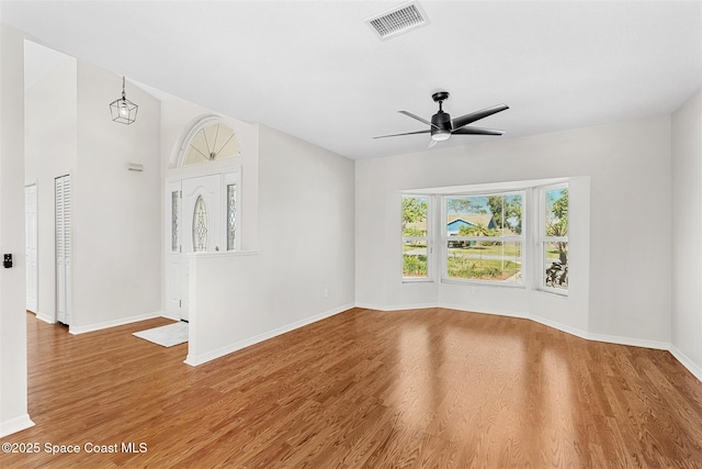 empty room featuring ceiling fan with notable chandelier and wood-type flooring