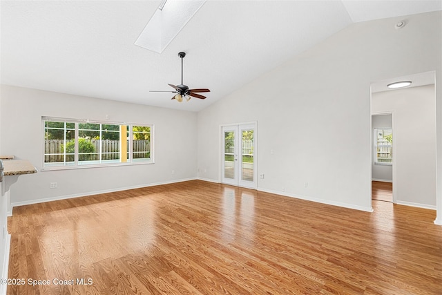 unfurnished living room with high vaulted ceiling, ceiling fan, a skylight, and light hardwood / wood-style flooring