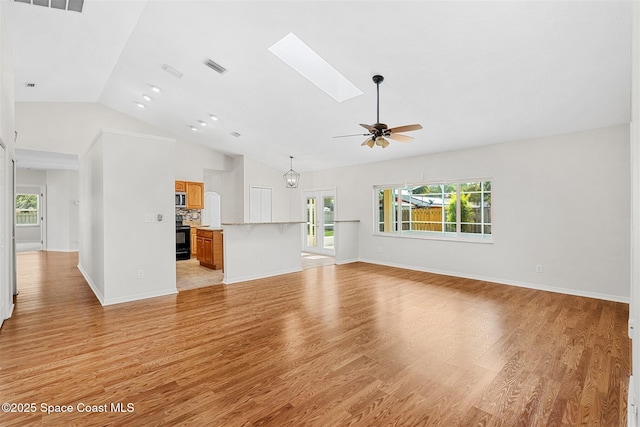 unfurnished living room featuring ceiling fan, vaulted ceiling with skylight, and light wood-type flooring