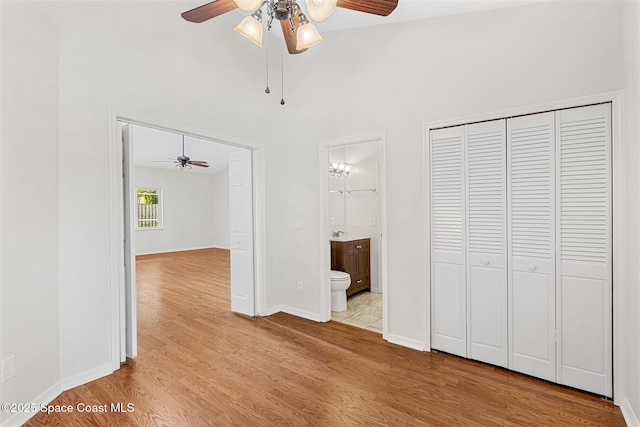 unfurnished bedroom featuring ceiling fan, light hardwood / wood-style flooring, connected bathroom, and a closet