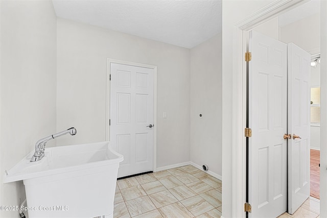 bathroom with a textured ceiling, a tub to relax in, and sink