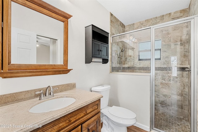 bathroom featuring toilet, an enclosed shower, ceiling fan, and vanity