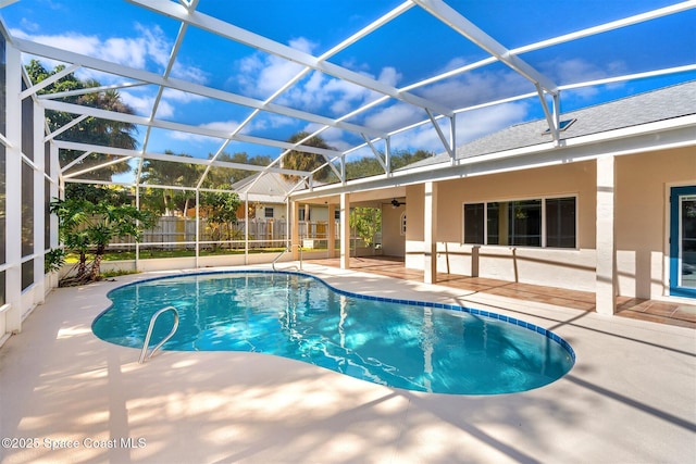 view of swimming pool with a patio area, ceiling fan, and glass enclosure