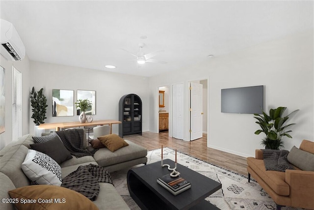 living room with ceiling fan, light hardwood / wood-style floors, and a wall mounted air conditioner