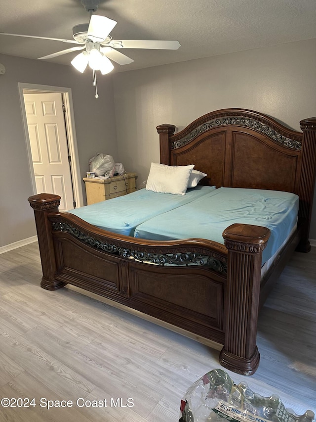 bedroom with ceiling fan, light hardwood / wood-style floors, and a textured ceiling