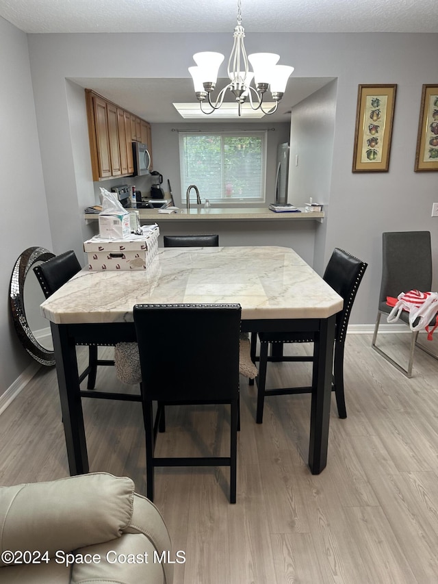 dining area featuring sink, light hardwood / wood-style flooring, and a chandelier