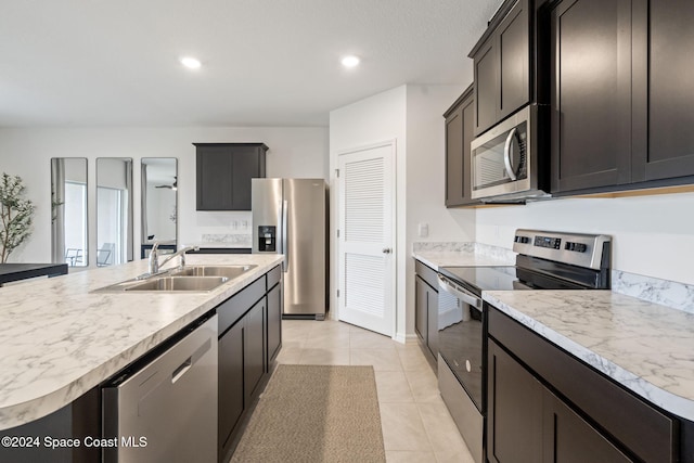 kitchen with light tile patterned flooring, sink, stainless steel appliances, and an island with sink