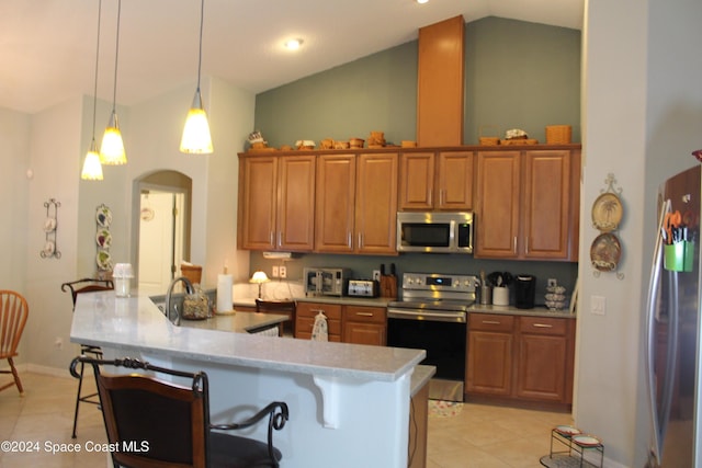 kitchen with stainless steel appliances, kitchen peninsula, decorative light fixtures, a breakfast bar area, and light tile patterned flooring