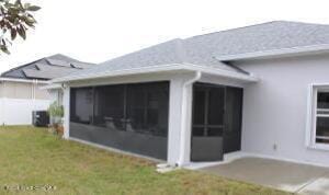 rear view of house with a sunroom, cooling unit, and a lawn