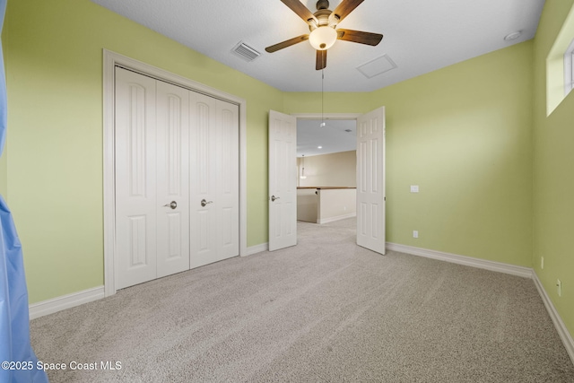 unfurnished bedroom featuring ceiling fan, light colored carpet, and a closet