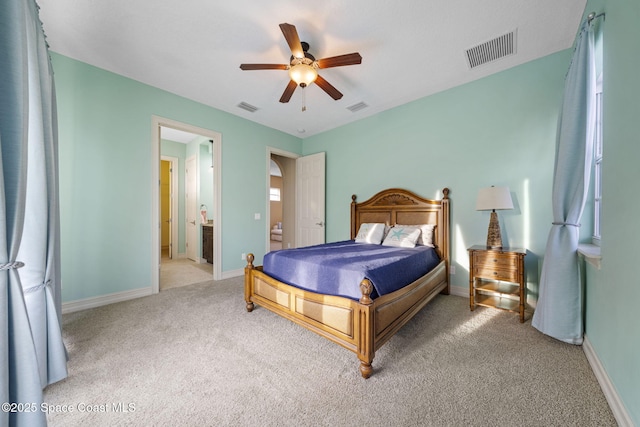 bedroom with ensuite bathroom, ceiling fan, and light colored carpet