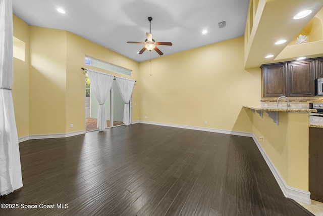 unfurnished living room featuring dark hardwood / wood-style flooring, ceiling fan, and sink