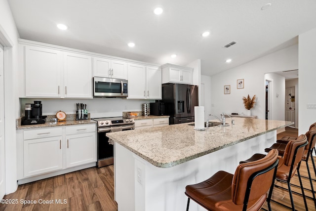 kitchen featuring appliances with stainless steel finishes, a kitchen island with sink, sink, white cabinets, and dark hardwood / wood-style floors