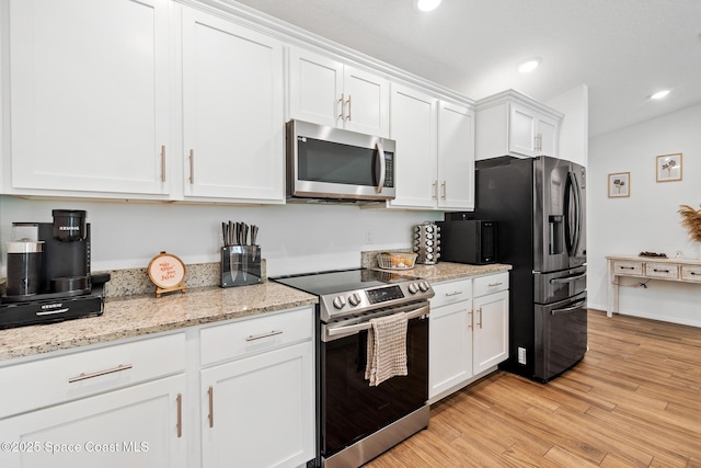 kitchen with light stone countertops, white cabinets, light wood-type flooring, and appliances with stainless steel finishes