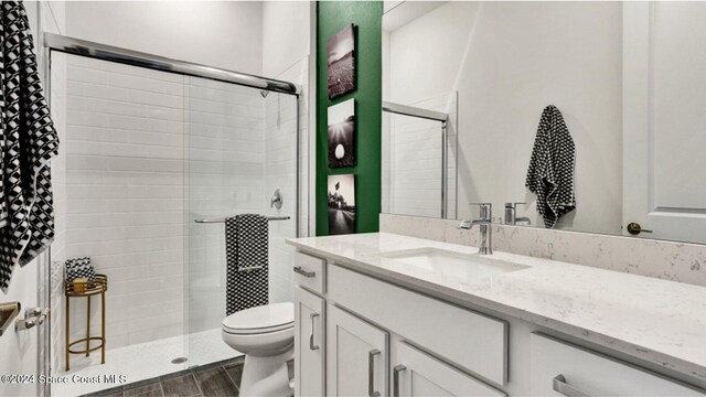 bathroom featuring vanity, a shower with shower door, and toilet