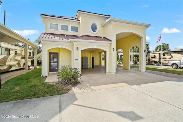 mediterranean / spanish home featuring a front yard and a carport