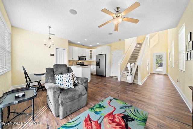 living room featuring ceiling fan with notable chandelier and dark hardwood / wood-style floors