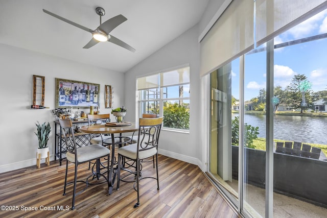 dining area featuring hardwood / wood-style floors, a water view, ceiling fan, and lofted ceiling