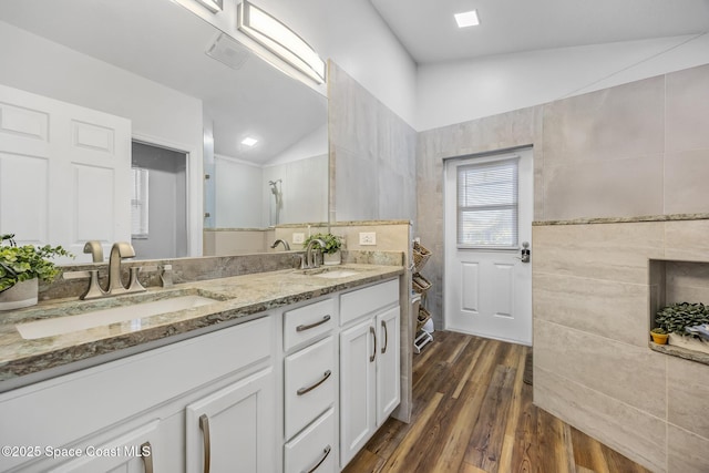 bathroom with tile walls, hardwood / wood-style floors, vanity, and lofted ceiling