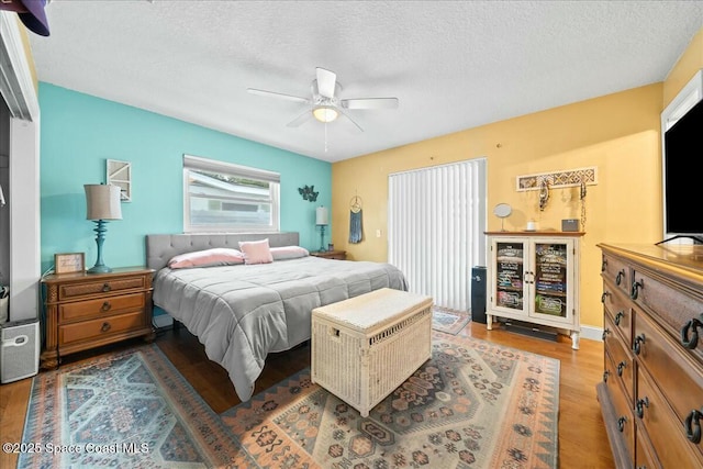 bedroom featuring ceiling fan, hardwood / wood-style floors, and a textured ceiling