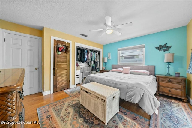 bedroom with ceiling fan, light wood-type flooring, and a textured ceiling