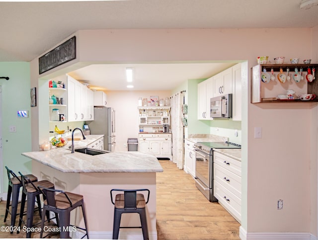 kitchen with open shelves, stainless steel appliances, a sink, a peninsula, and a kitchen bar